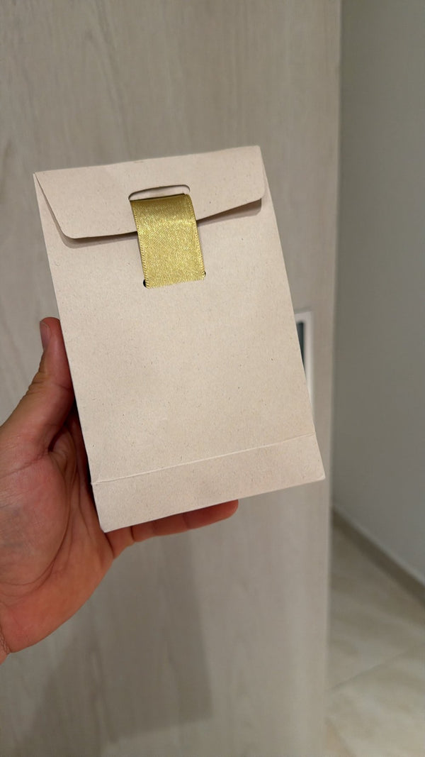 Sobre kraft con cinta dorada en el que van los llaveros